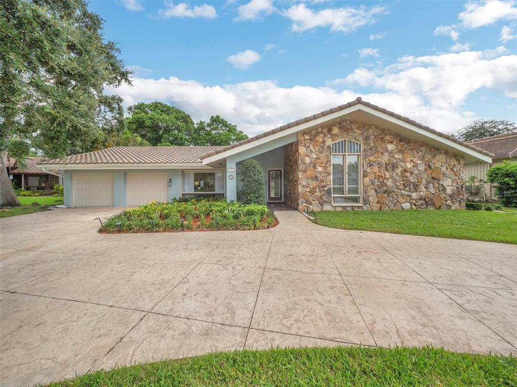 A single-story house features a stone facade, a tiled roof, and a large concrete driveway — 9651 CONCH SHELL MANOR, PLANTATION, FL