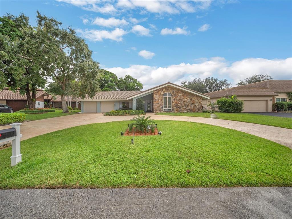 A single-story house with a stone facade, circular driveway, and a large front lawn — 9651 CONCH SHELL MANOR, PLANTATION, FL