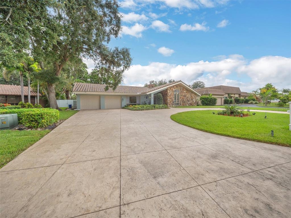 A single-story house with a stone facade, a two-car garage, and a large concrete driveway — 9651 CONCH SHELL MANOR, PLANTATION, FL