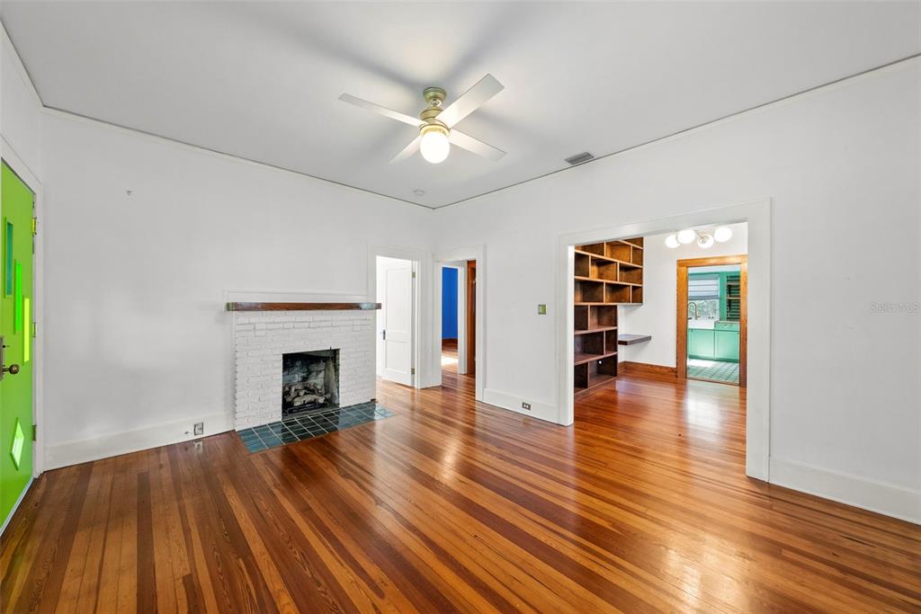 A living room with hardwood floors, a white brick fireplace, and a ceiling fan — 1024 23RD AVENUE N, ST PETERSBURG, FL