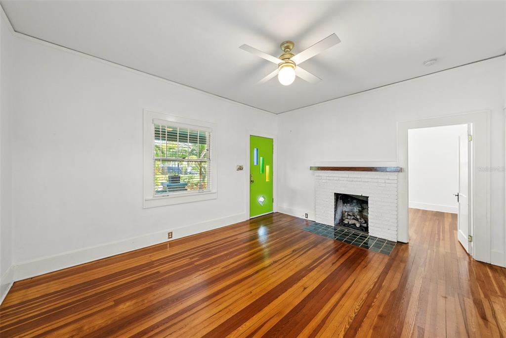 A living room with hardwood floors, a white brick fireplace, and a bright green door — 1024 23RD AVENUE N, ST PETERSBURG, FL