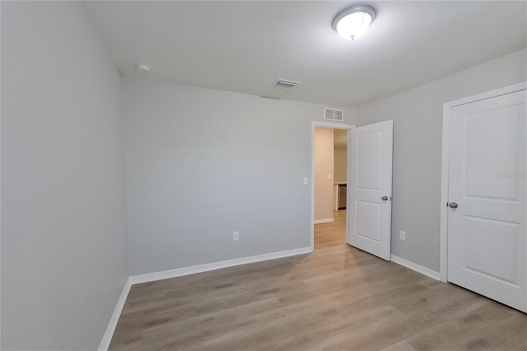 An empty room with light gray walls, wood-look flooring, and two white interior doors — 18310 GIBRALTAR LANE, LEHIGH ACRES, FL