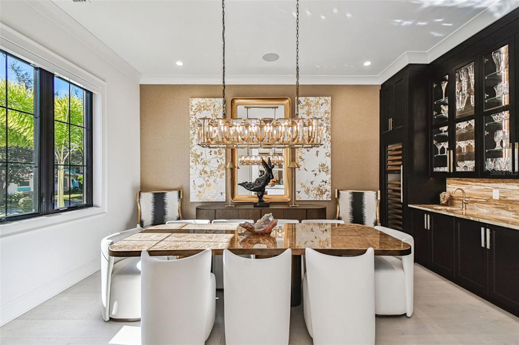 A dining room features a rectangular table, white chairs, a crystal chandelier, and dark cabinetry — 2915 W HARBOR VIEW AVENUE, TAMPA, FL