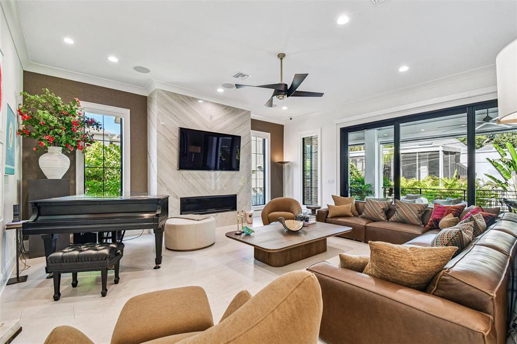 A living room features a grand piano, a marble fireplace, and a large sectional sofa — 2915 W HARBOR VIEW AVENUE, TAMPA, FL