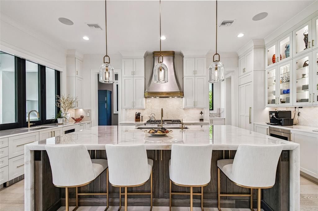 A modern kitchen features a large marble-topped island, white cabinetry, and three pendant lights — 2915 W HARBOR VIEW AVENUE, TAMPA, FL