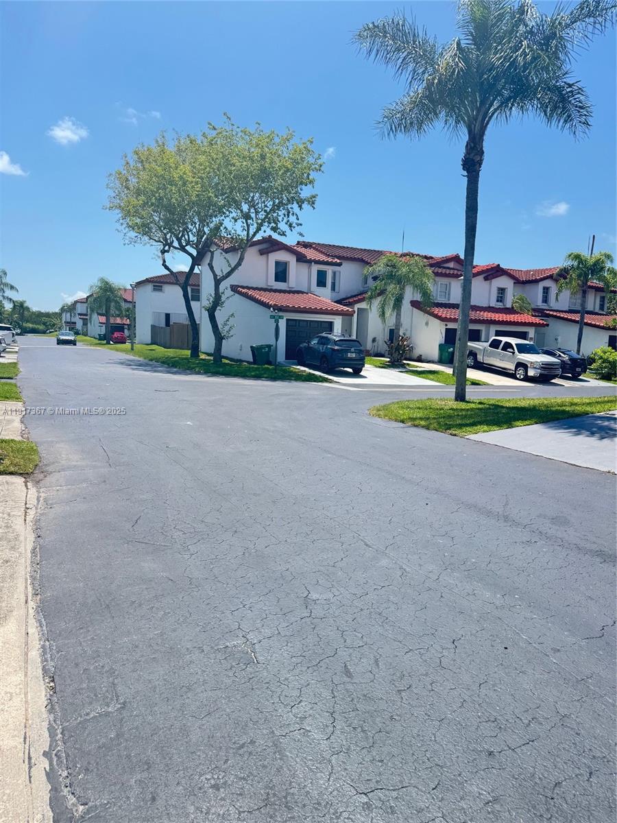 A street view of a residential neighborhood featuring two-story townhouses with red tile roofs — 8419 SW 209th St, Cutler Bay FL 33189, CUTLER BAY, FL