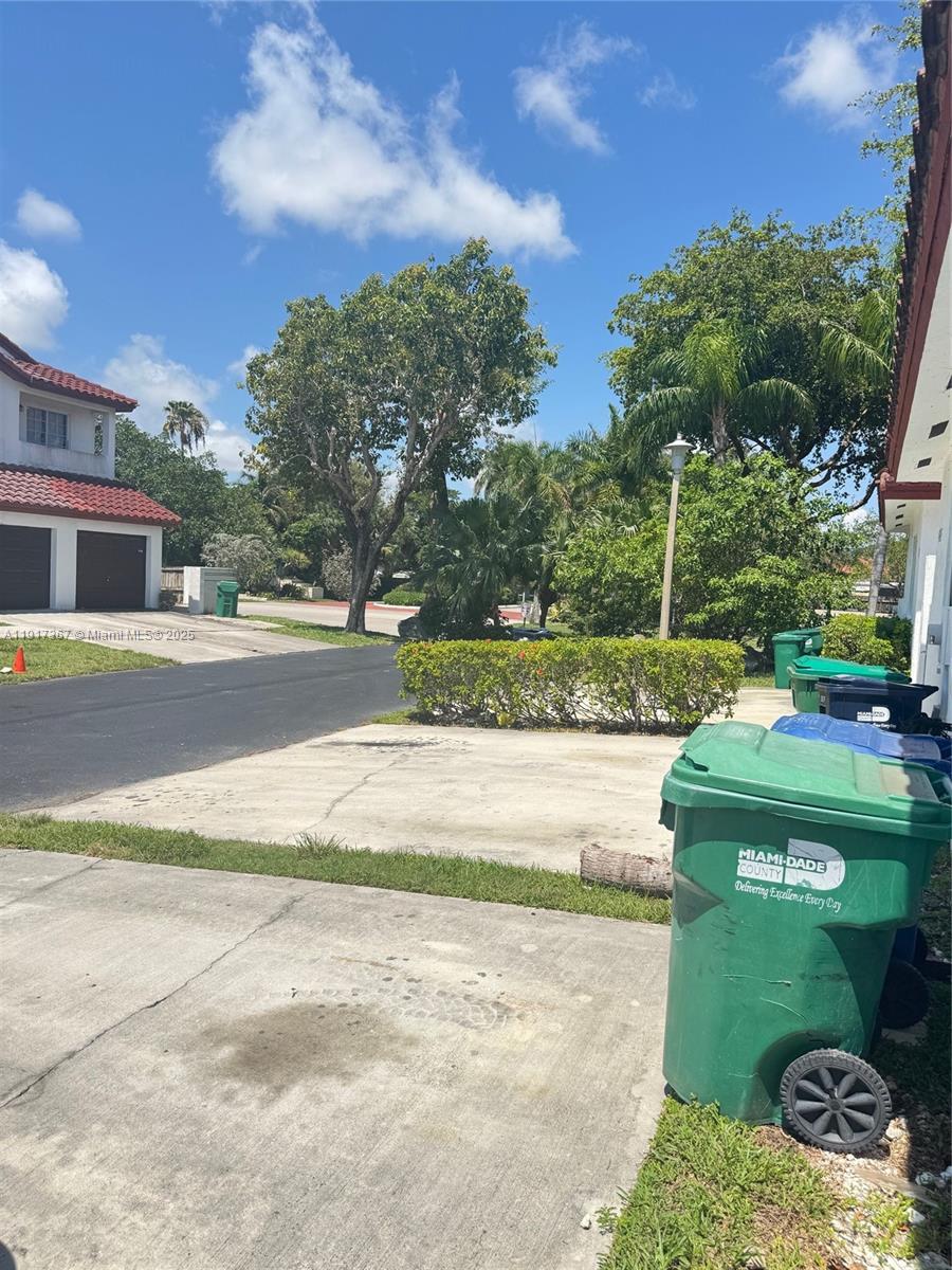 A view of a residential driveway with several trash bins and a nearby house — 8419 SW 209th St, Cutler Bay FL 33189, CUTLER BAY, FL