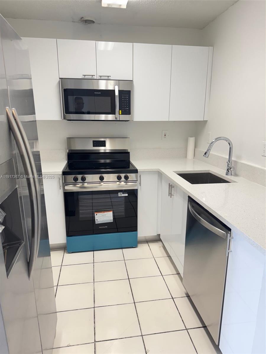 A modern kitchen features white cabinets, stainless steel appliances, and white countertops — 8419 SW 209th St, Cutler Bay FL 33189, CUTLER BAY, FL