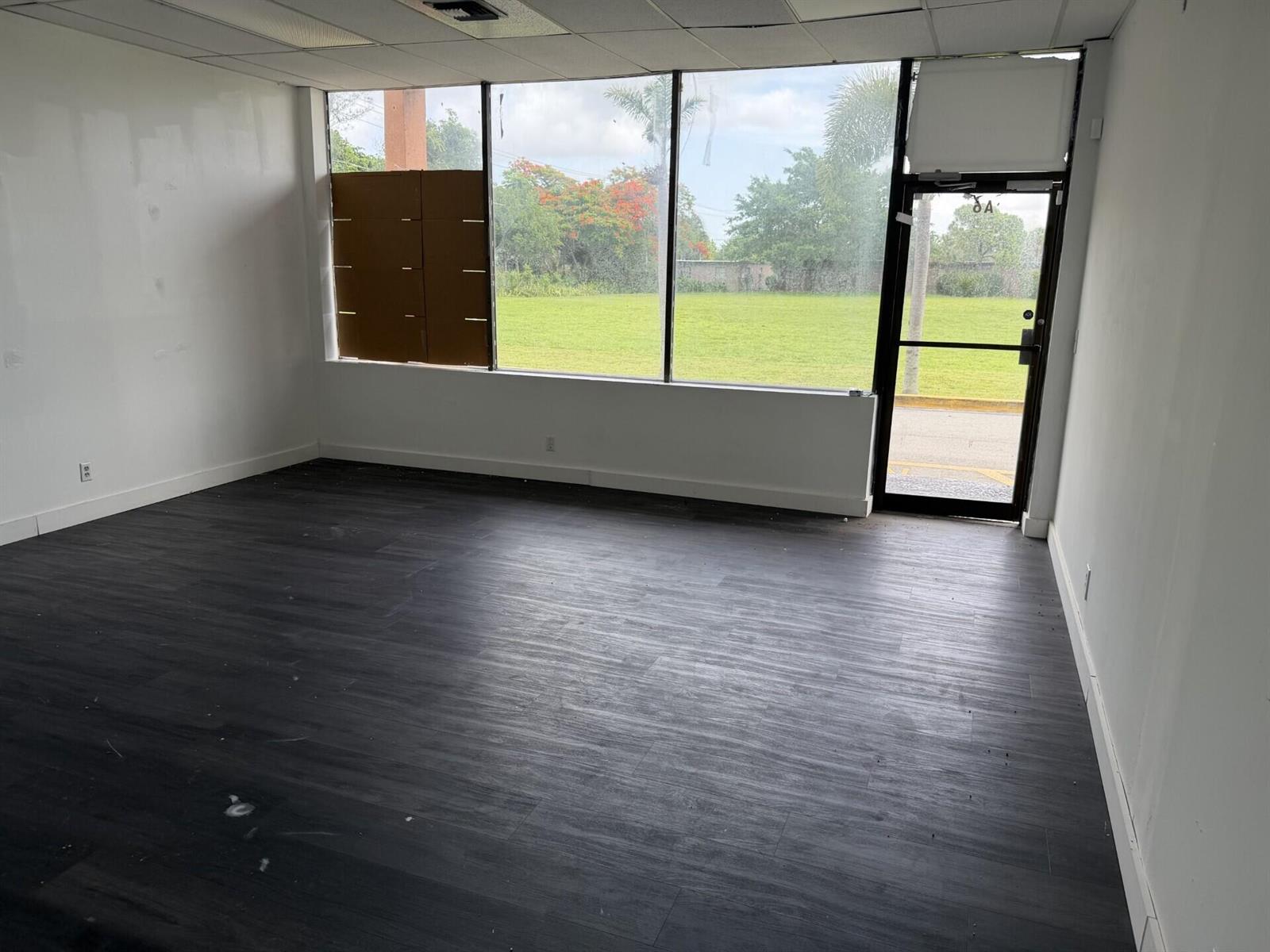 An empty commercial space with dark wood-look flooring, white walls, and large floor-to-ceiling windows — 1303 N State Road 7 # 6, Margate FL 33063, MARGATE, FL