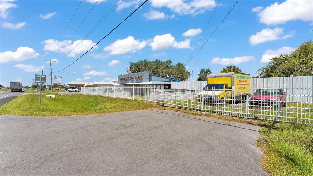 An exterior view shows a commercial building with a fenced lot containing a truck and car — 2999 US HIGHWAY 92, WINTER HAVEN, FL