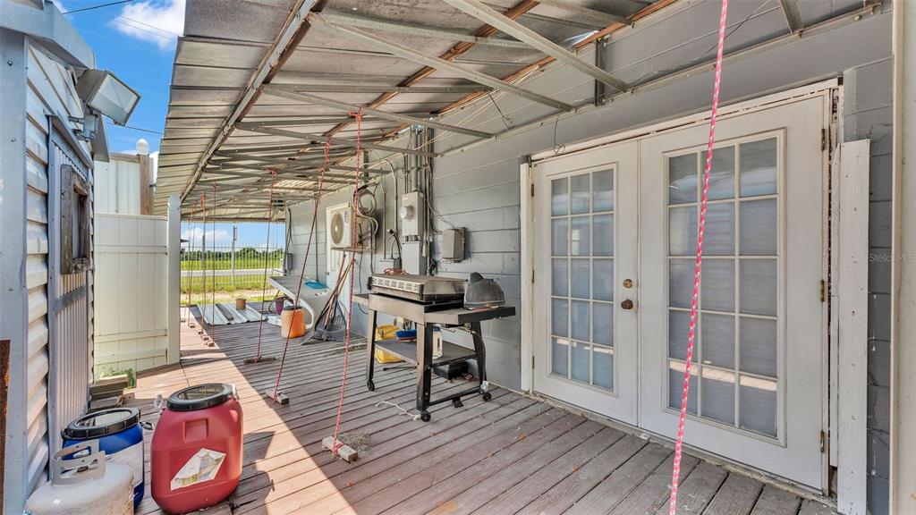 A wooden deck with a metal roof cover, a grill, and French doors — 2999 US HIGHWAY 92, WINTER HAVEN, FL