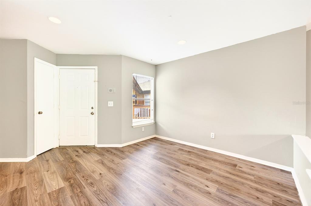 An empty room features light gray walls, wood-look flooring, a white door, and a window — 474 S PIN OAK PLACE UNIT 308, LONGWOOD, FL