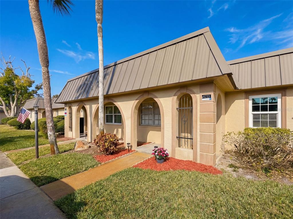 A single-story tan stucco building with a metal roof and arched entryway — 4233 STRATFORD DRIVE UNIT D, NEW PORT RICHEY, FL