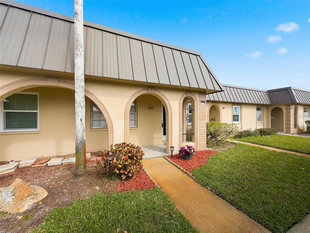 A tan single-story building with a metal roof, arched entryways, and a concrete walkway — 4233 STRATFORD DRIVE UNIT D, NEW PORT RICHEY, FL