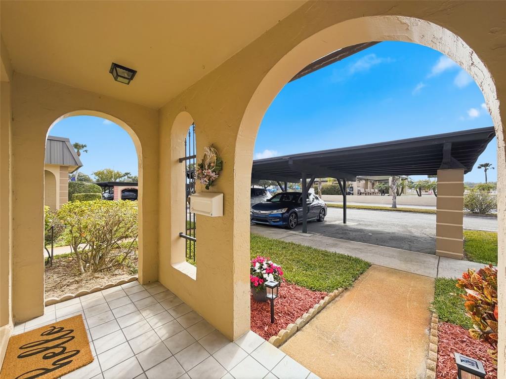 A tiled entryway porch features arched openings, a mailbox, and a view of a carport — 4233 STRATFORD DRIVE UNIT D, NEW PORT RICHEY, FL