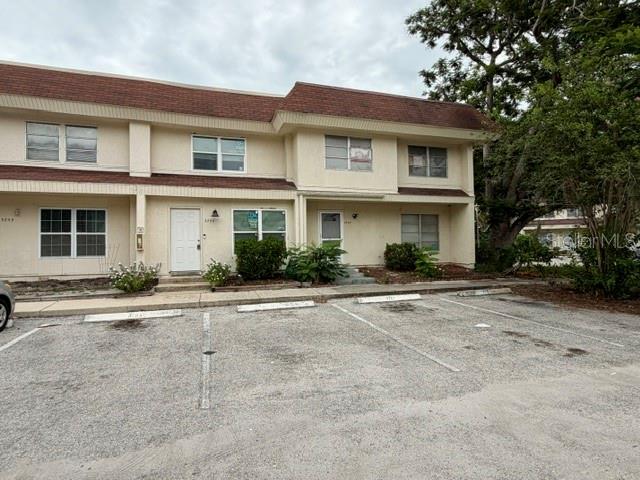 A two-story townhouse exterior features a brown shingled roof and a gravel parking lot — 3755 AMHERST WAY UNIT 34, SARASOTA, FL