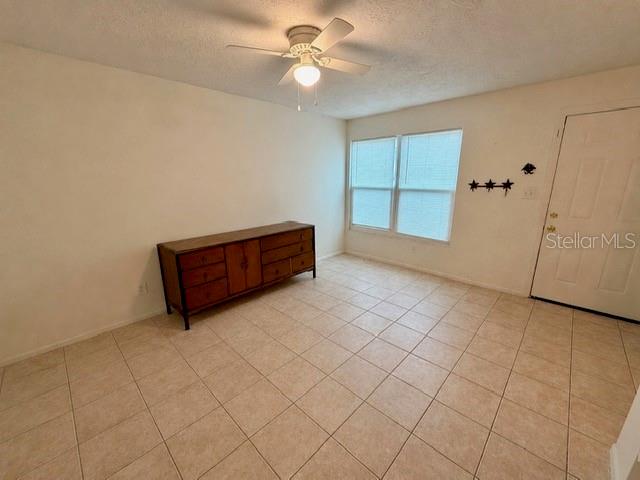 A room with light-colored tile flooring, a wooden dresser, and a ceiling fan — 3755 AMHERST WAY UNIT 34, SARASOTA, FL