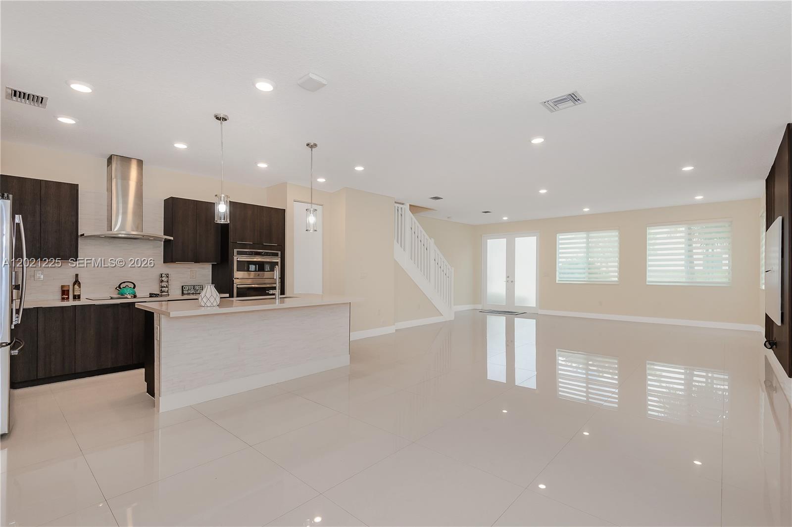 A modern open-concept kitchen and living area features dark cabinetry, a light island, and tile floors — 6681 NW 104th Ave, Doral FL 33178, DORAL, FL