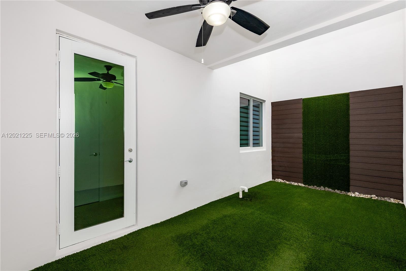 This outdoor patio features artificial turf, a ceiling fan, and a decorative wood-paneled wall — 6681 NW 104th Ave, Doral FL 33178, DORAL, FL