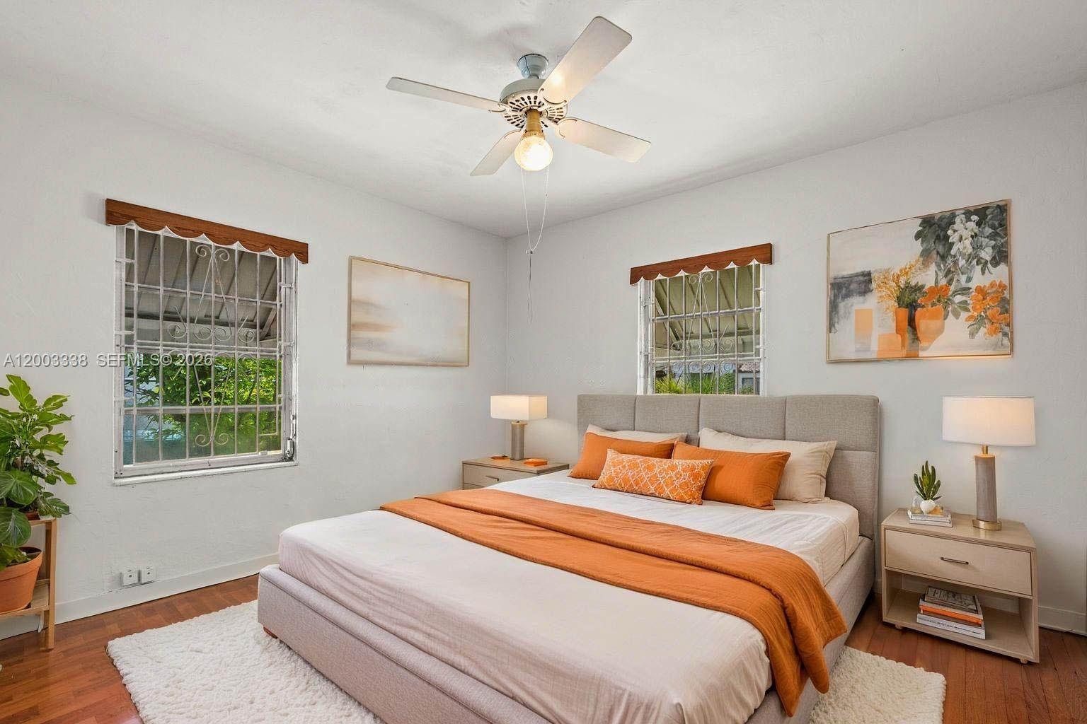 A bedroom features a bed with orange bedding, two nightstands, and windows with security bars — 1879 SW 16th St, Miami FL 33145, MIAMI, FL