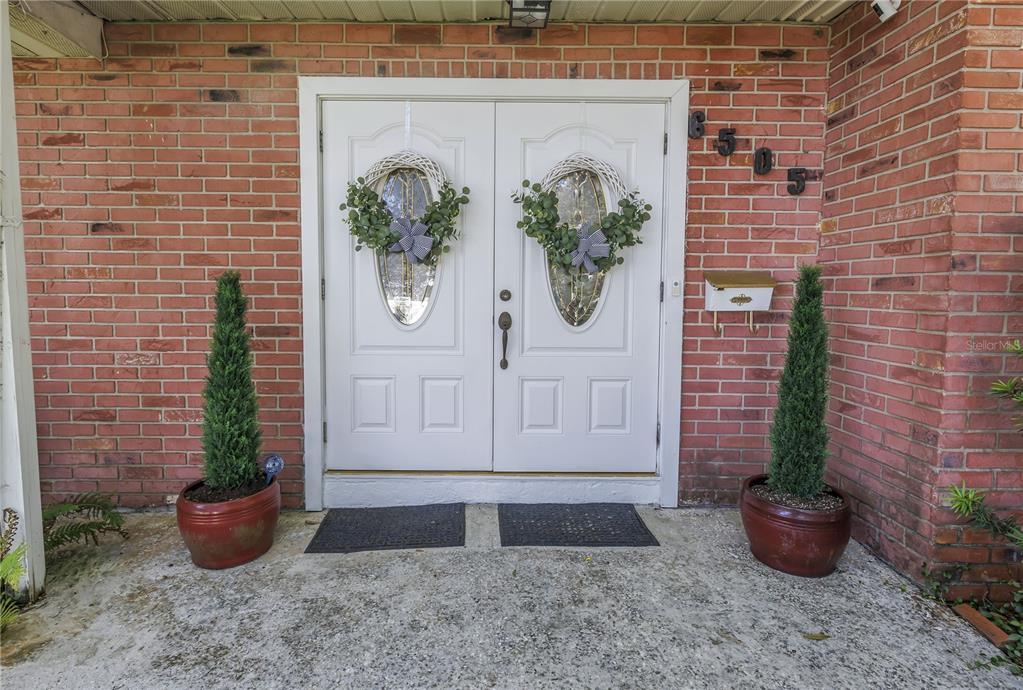 A brick exterior features a white double front door with wreaths and two potted topiaries — 6505 CEDAR STREET NE, ST PETERSBURG, FL