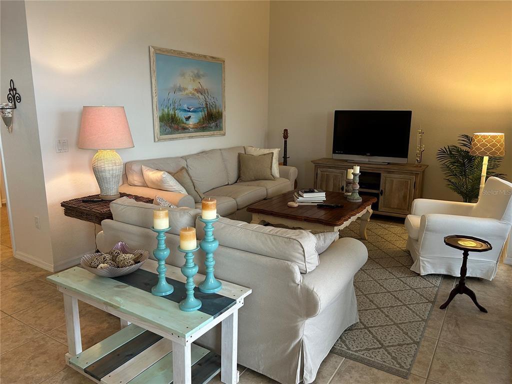 A living room features a beige sofa, a coffee table, and a television on a console — 17110 TERRAVERDE CIRCLE UNIT 2415, FORT MYERS, FL