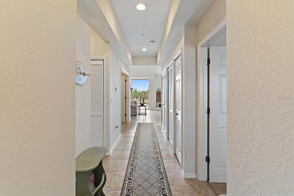 A tiled hallway with a runner rug leads toward an open living area and balcony — 17110 TERRAVERDE CIRCLE UNIT 2415, FORT MYERS, FL