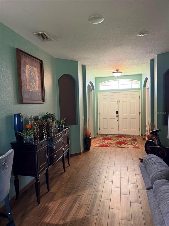 A foyer with wood-look tile flooring leads to a double-door entryway with an arched transom — 1504 LAKE THOMAS LOOP, WINTER HAVEN, FL