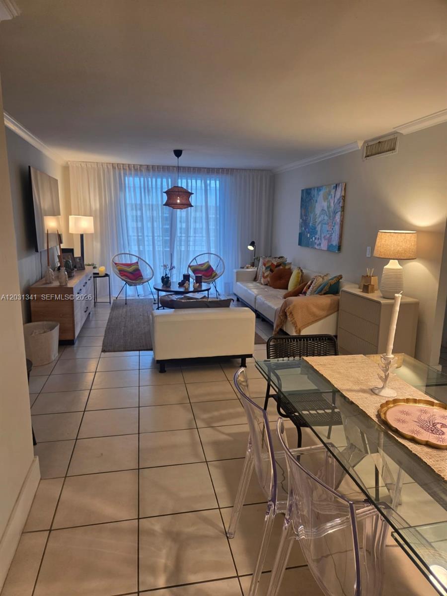 A living room with tile floors, a white sofa, and a dining area — 5555 Collins Ave # 16W, Miami Beach FL 33140, MIAMI BEACH, FL