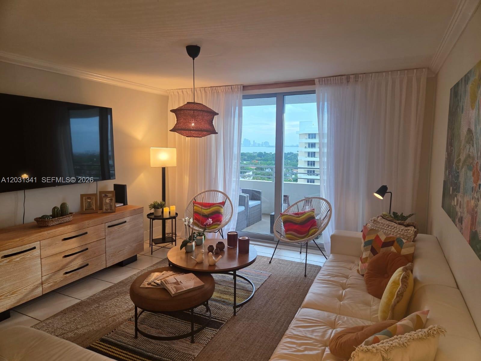 A living room features a white sofa, wooden media console, two accent chairs, and balcony access — 5555 Collins Ave # 16W, Miami Beach FL 33140, MIAMI BEACH, FL