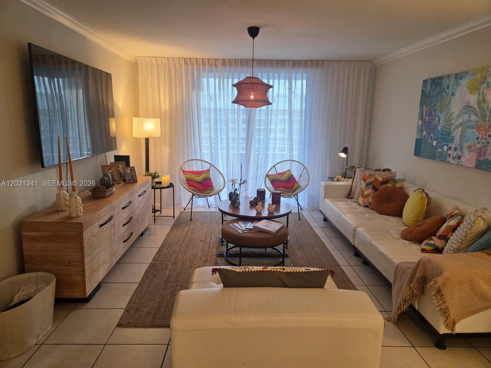 A living room features a white sofa, two accent chairs, a wooden console, and sheer curtains — 5555 Collins Ave # 16W, Miami Beach FL 33140, MIAMI BEACH, FL