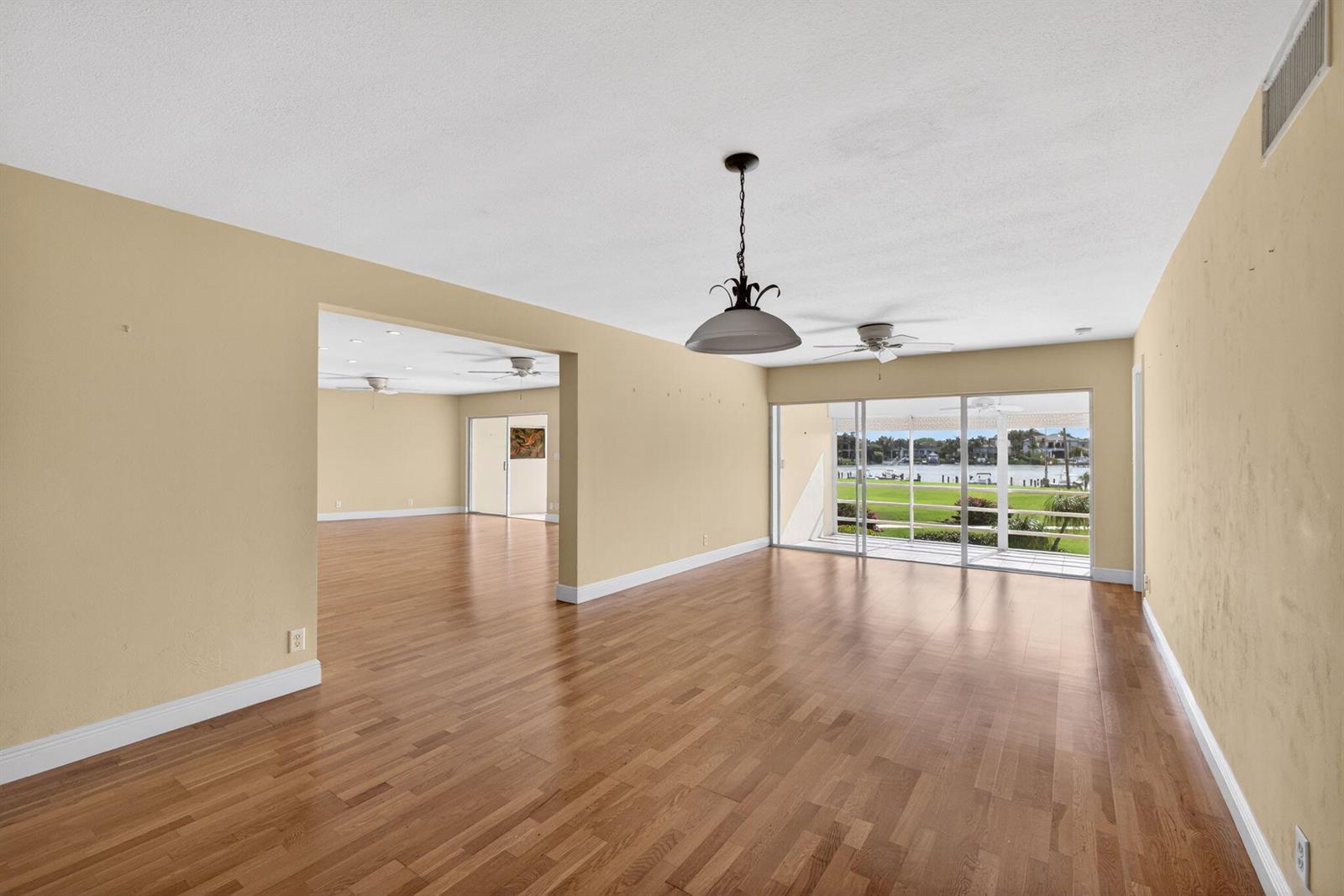 An empty living area with hardwood floors, a hanging light fixture, and large sliding glass doors — 478 Tequesta Drive # 205, Tequesta FL 33469, TEQUESTA, FL
