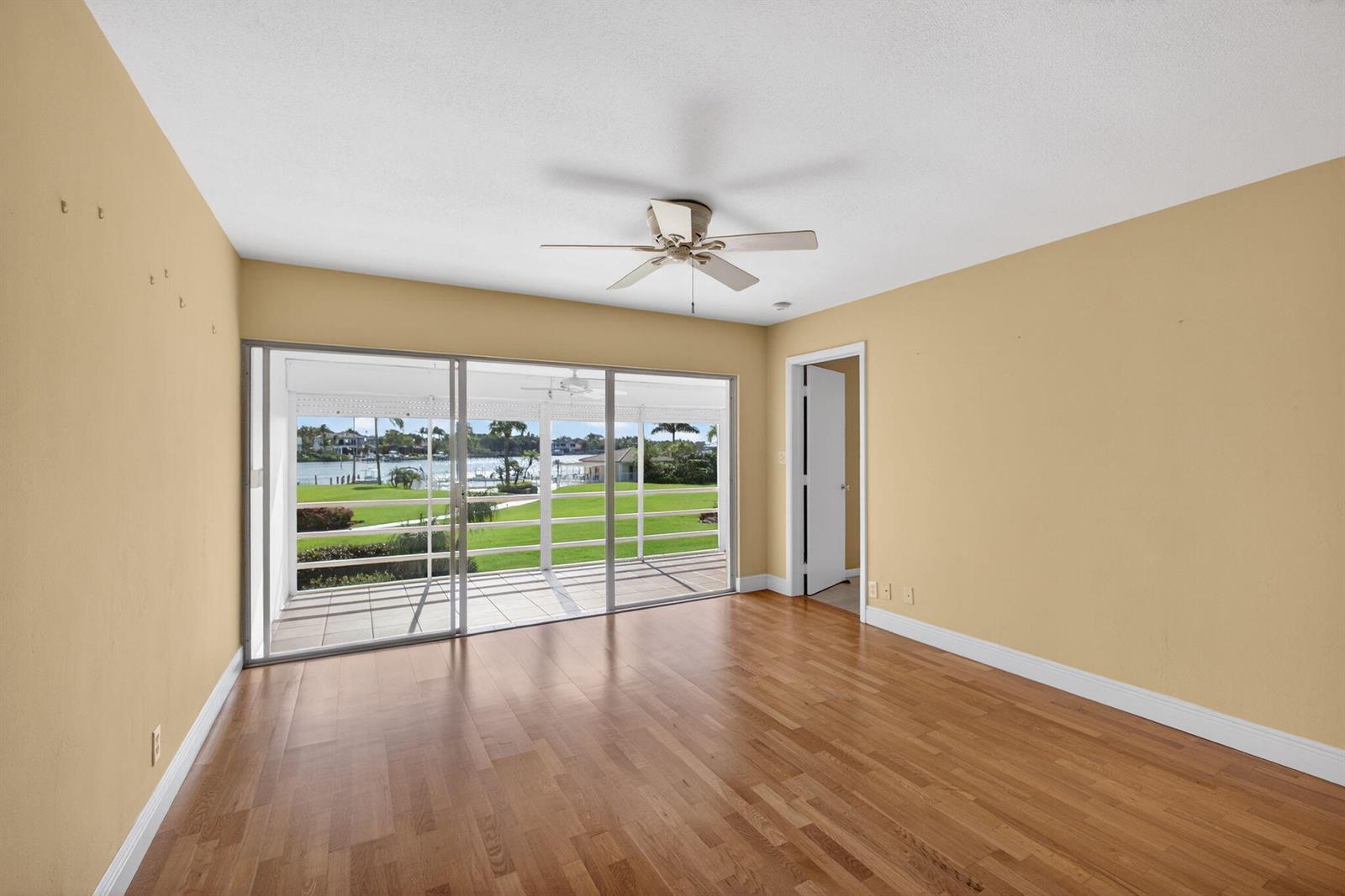 An empty room with hardwood floors, tan walls, a ceiling fan, and sliding glass doors — 478 Tequesta Drive # 205, Tequesta FL 33469, TEQUESTA, FL