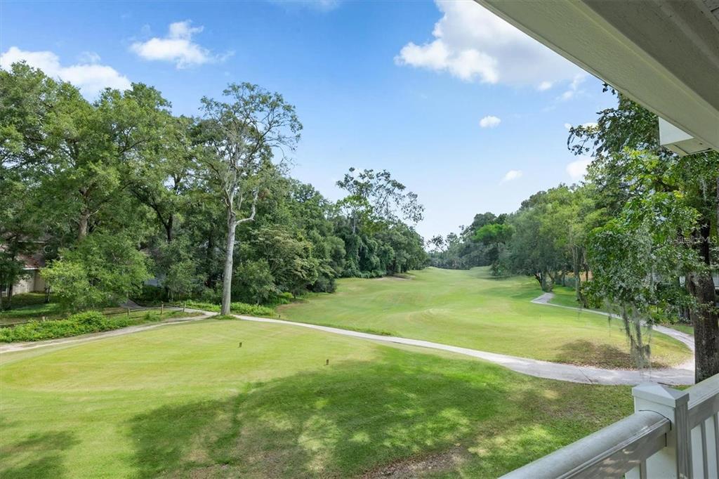 A view from a balcony overlooking a golf course fairway surrounded by mature trees — 10000 SW 52ND AVENUE UNIT EE 183, GAINESVILLE, FL