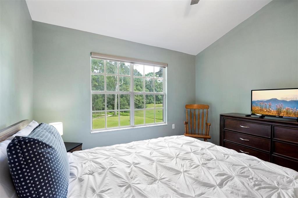 A bedroom features a bed with a white comforter, a dresser with a television, and a window — 10000 SW 52ND AVENUE UNIT EE 183, GAINESVILLE, FL