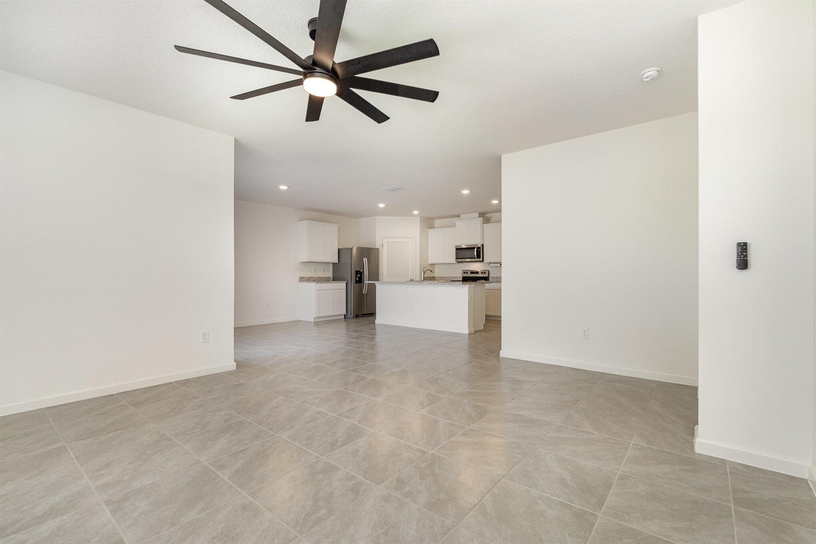 An open-concept living area features light tile flooring, white walls, and a modern kitchen — GRANT VALKARIA, FL