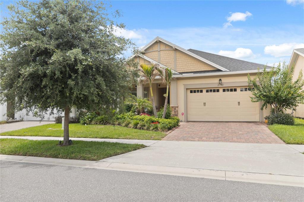 A single-story house with a tan exterior, a two-car garage, and a landscaped front yard — 2740 SOUTHLAND STREET, ST CLOUD, FL