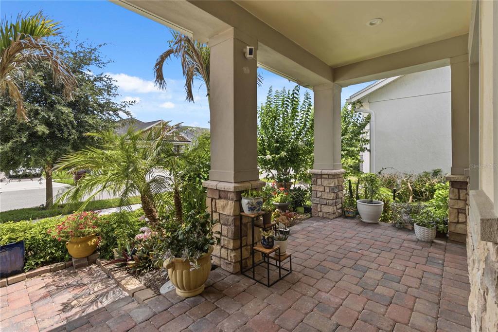 A covered front porch features stone-based columns, a brick paver floor, and various potted plants — 2740 SOUTHLAND STREET, ST CLOUD, FL