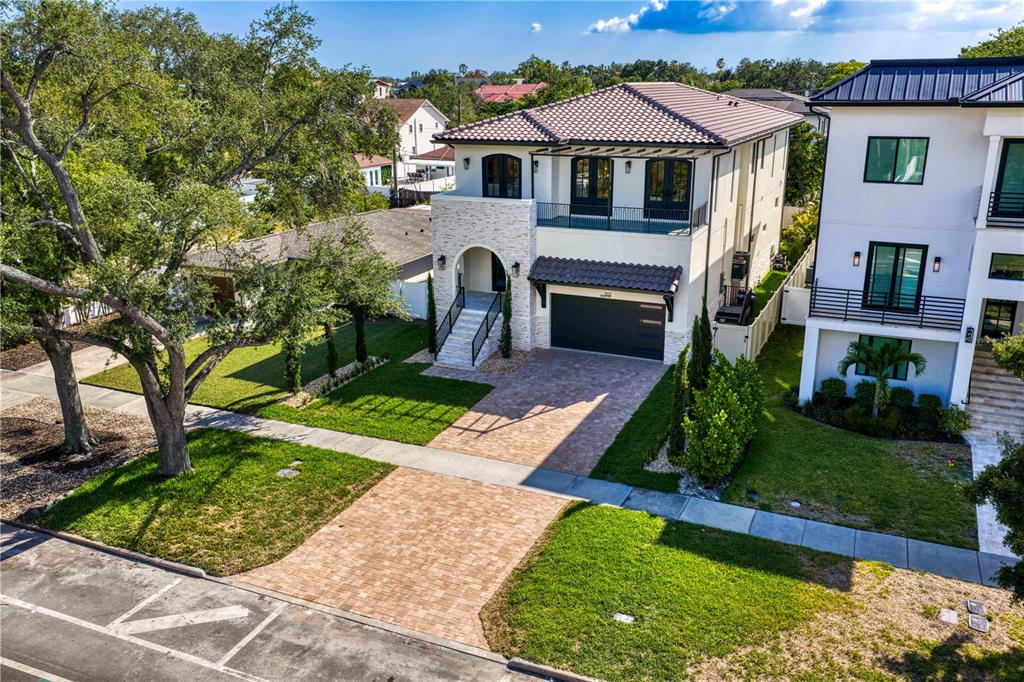 An aerial view of a two-story house with a stone facade, balcony, and paved driveway — 502 E DAVIS BOULEVARD, TAMPA, FL