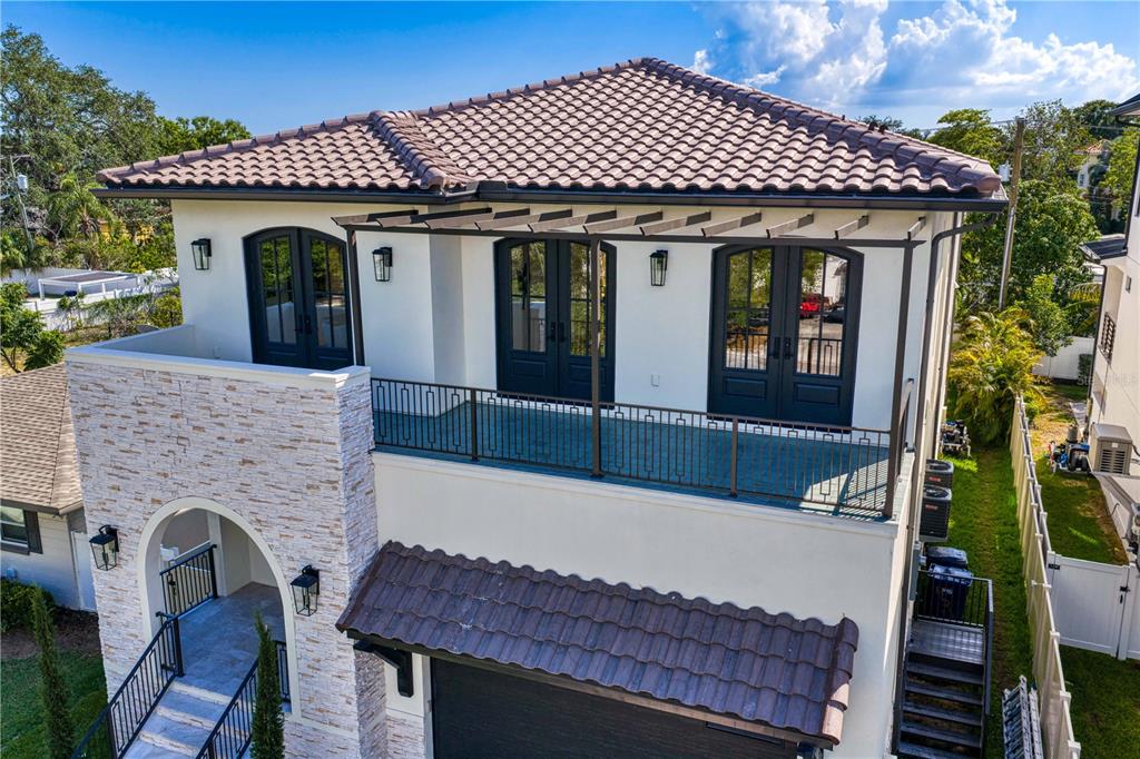 An exterior view of a two-story house featuring a stone facade, balcony, and tiled roof — 502 E DAVIS BOULEVARD, TAMPA, FL