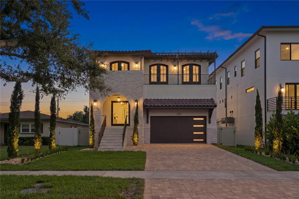 A two-story house with a stone facade, a balcony, and a paved driveway at dusk — 502 E DAVIS BOULEVARD, TAMPA, FL