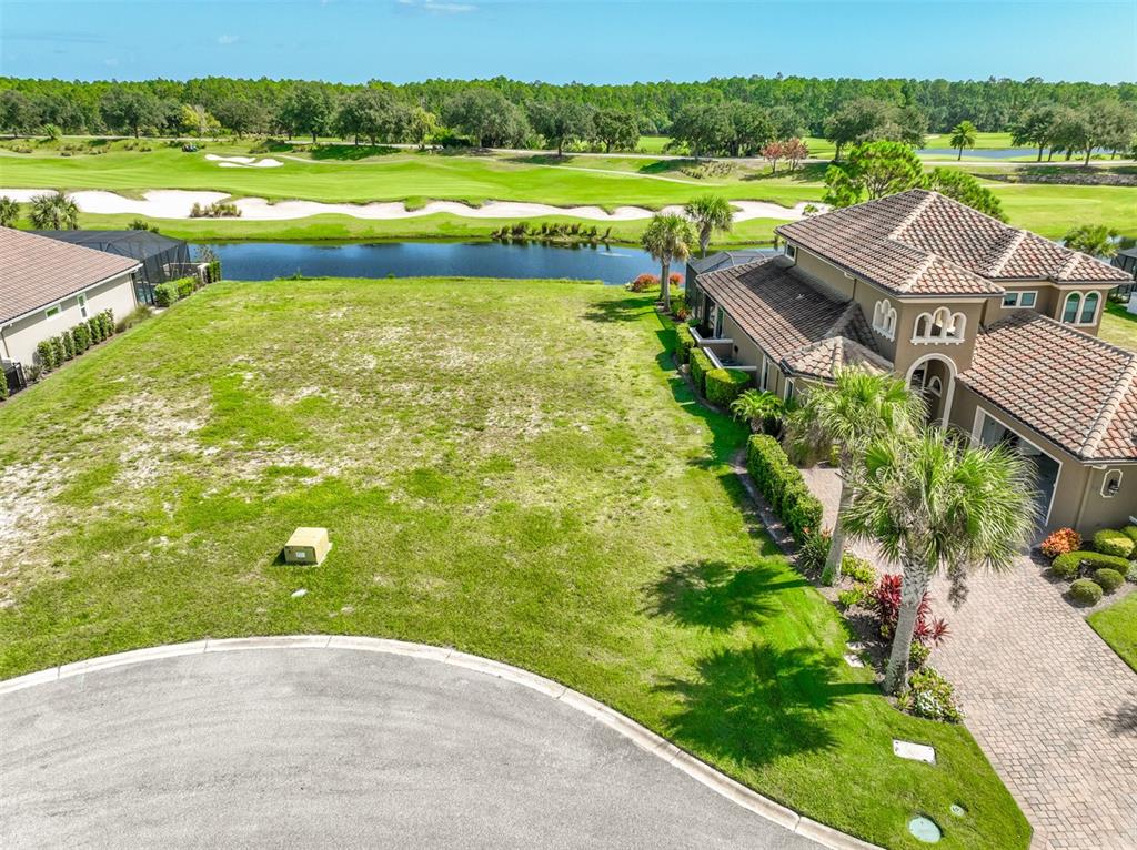 An aerial view shows a vacant residential lot next to a house overlooking a golf course — 359 HIBISCUS WAY, PALM COAST, FL