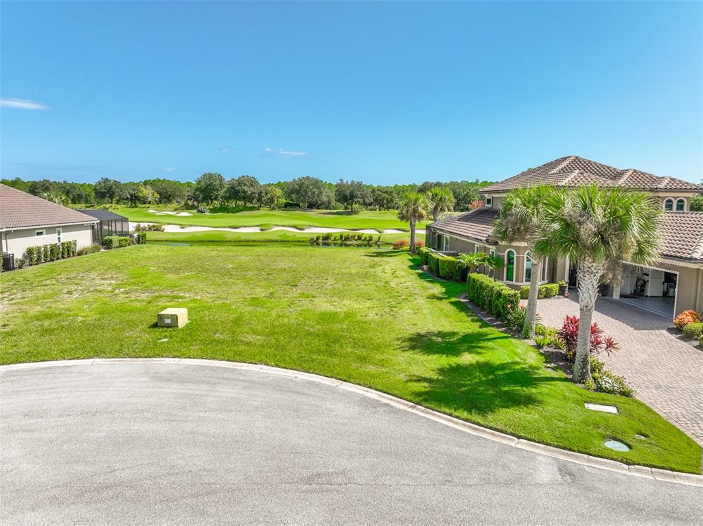 An aerial view shows a grassy lot next to a house overlooking a golf course — 359 HIBISCUS WAY, PALM COAST, FL
