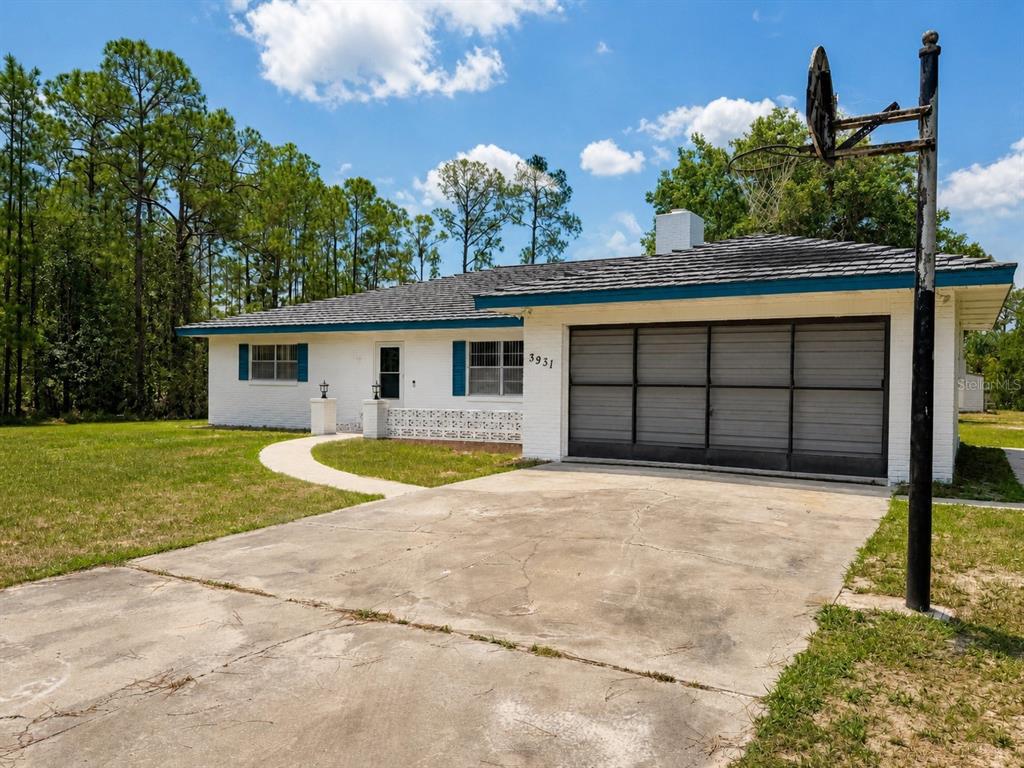 A white brick house exterior features a front porch with decorative block walls and lamps — 3931 GAILLARDIA DRIVE, INDIAN LAKE ESTATES, FL
