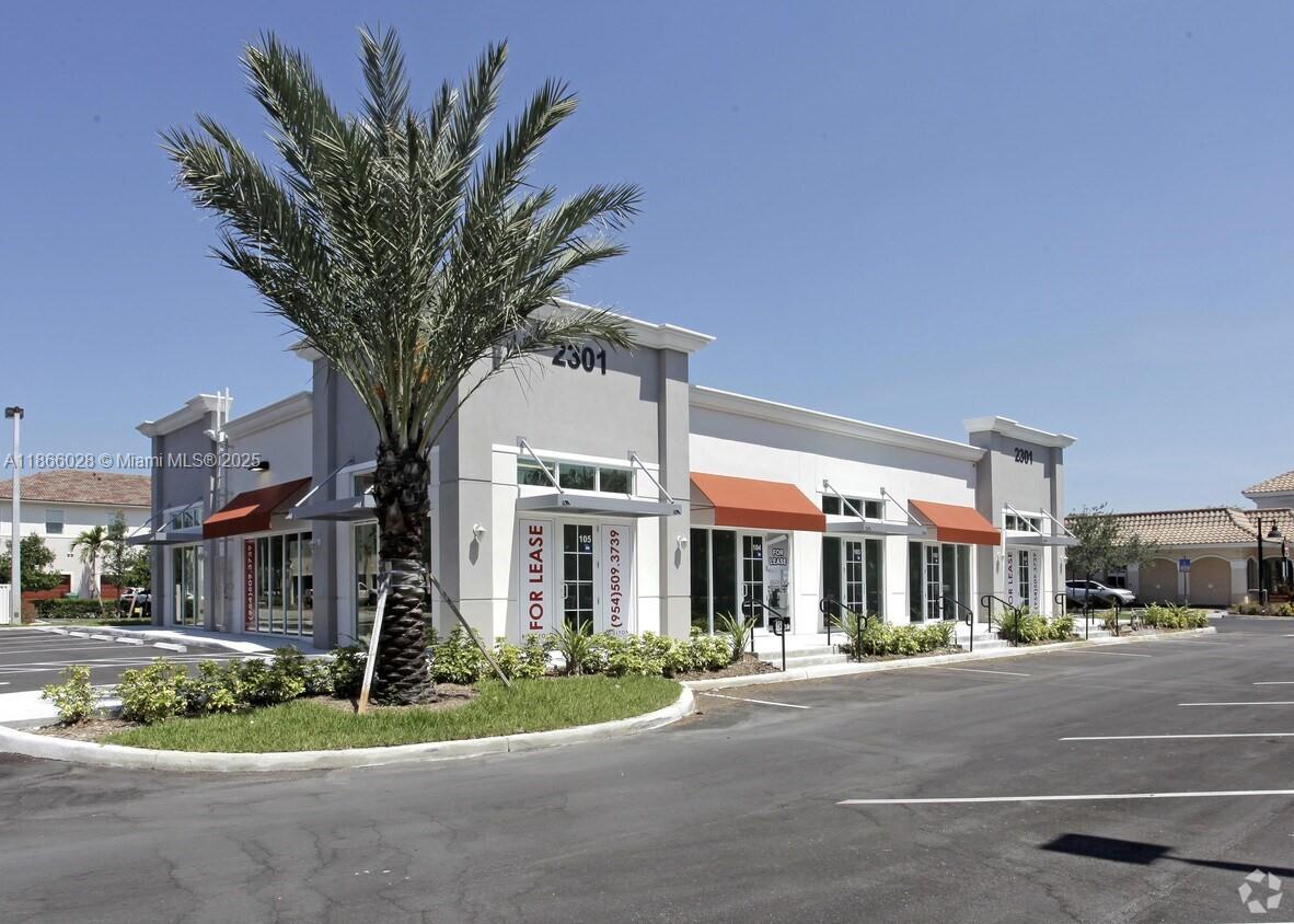 A modern, single-story commercial building with orange awnings and a palm tree in front — 2301 Palm Ave # 102, Miramar FL 33025, MIRAMAR, FL