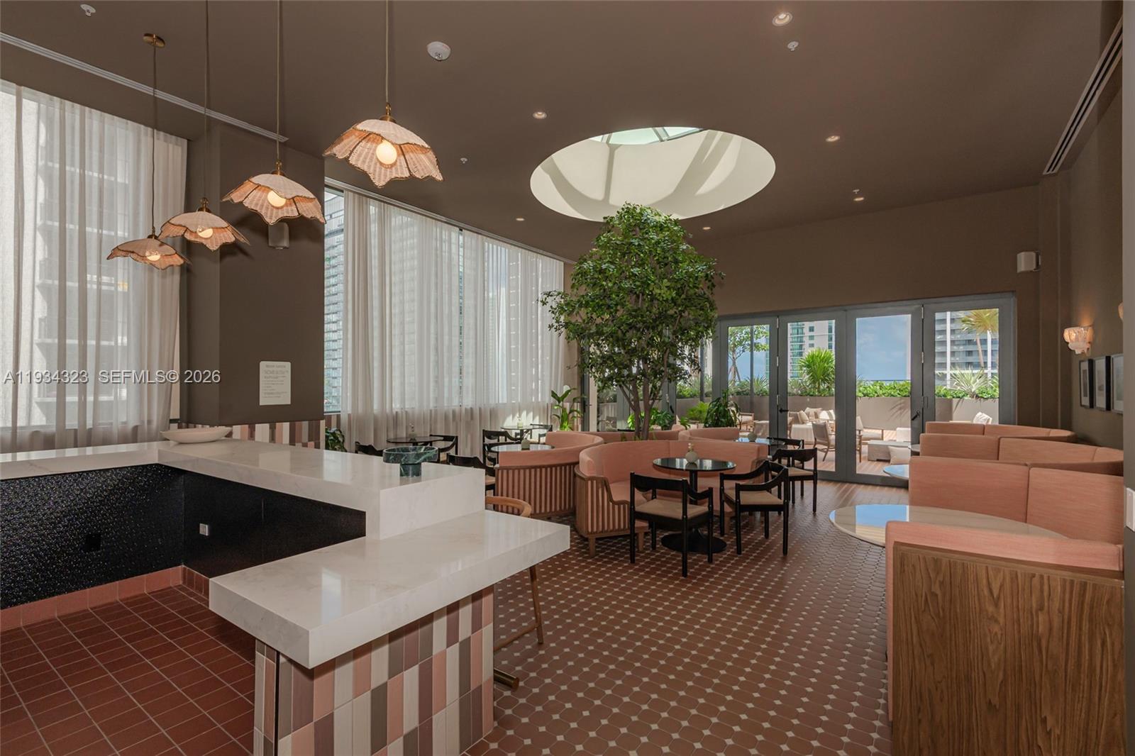 A lounge area features a bar, pink curved booths, a central tree, and a skylight — 11 NE 6 ST # 1407, Miami FL 33132, MIAMI, FL