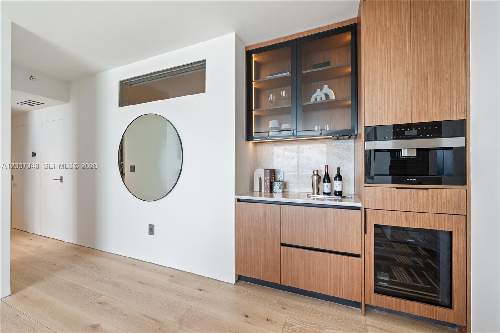 A modern wet bar features wood cabinetry, a built-in coffee machine, and a wine refrigerator — 6365 Collins Ave # 3904, Miami Beach FL 33141, MIAMI BEACH, FL