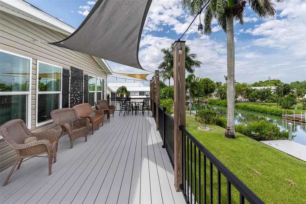 A spacious deck features wicker chairs, a dining set, shade sails, and a canal view — 3118 BAYBERRY AVENUE, PUNTA GORDA, FL