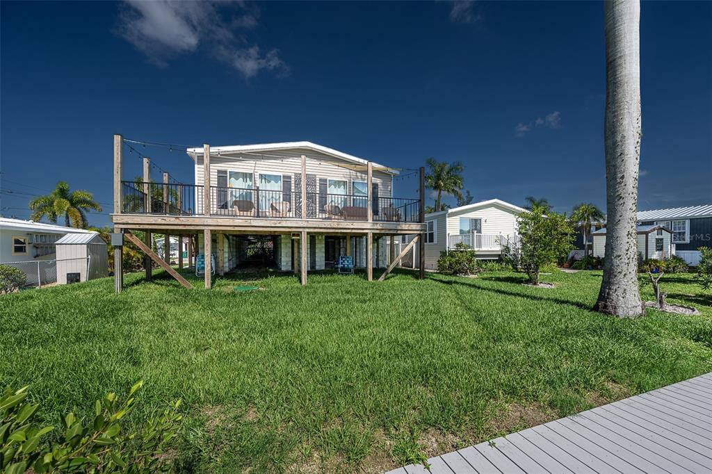 An elevated house with a large wooden deck stands in a grassy yard — 3118 BAYBERRY AVENUE, PUNTA GORDA, FL