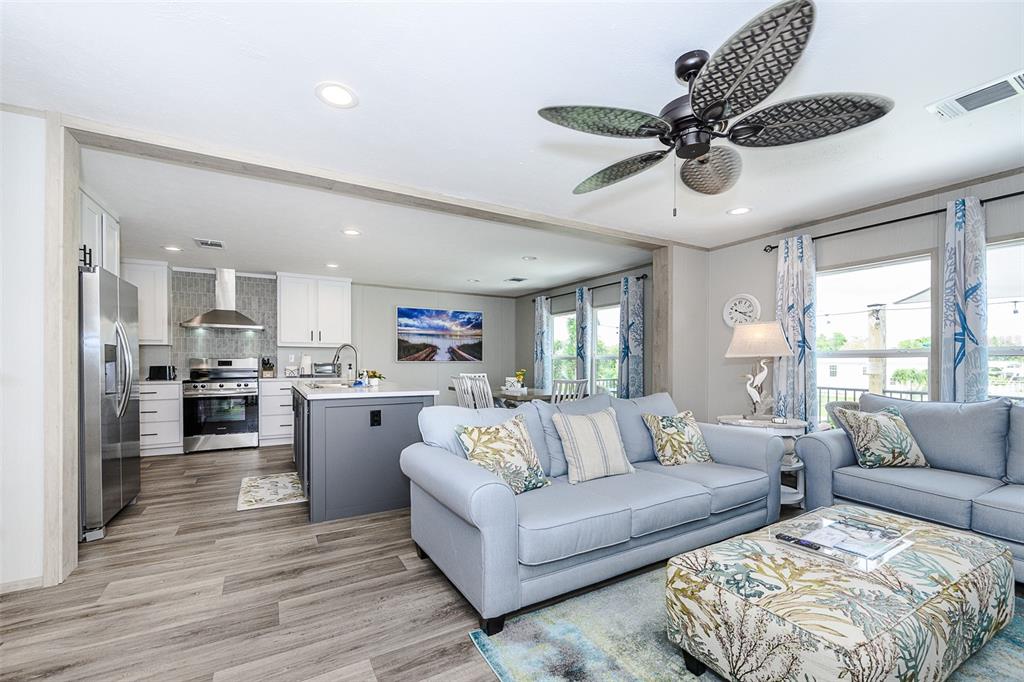 An open-concept living room and kitchen featuring light wood flooring and a ceiling fan — 3118 BAYBERRY AVENUE, PUNTA GORDA, FL